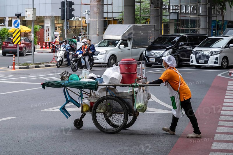 Street crossing woman with cookshop, Bangkok, Thailand