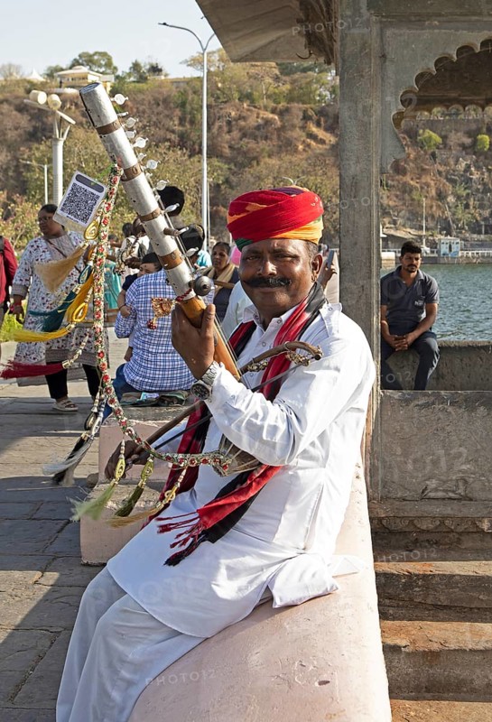 Indian man playing a long-necked spit lute or Ravanahattha at Lake Fateh Sagar, Udaipur, Rajasthan, India