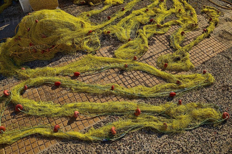 Yellow fishing nets spread on a stony ground on a sunny day, Agia Marina, Leros, Dodecanese, Greek Islands, Greece
