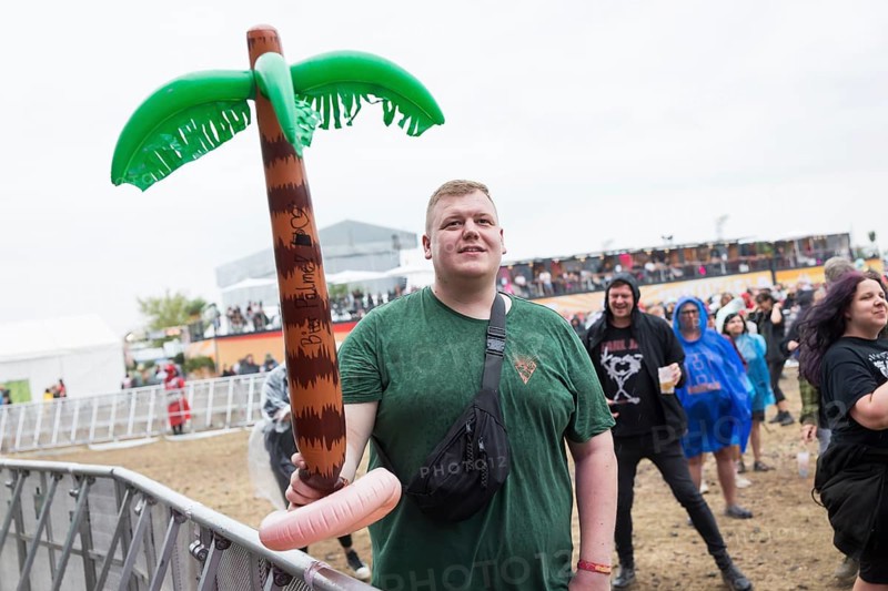 A festival visitor stands with an inflatable palm tree in the rain at the Highfield Festival on Sunday, Störmthaler See, 18/08/2024