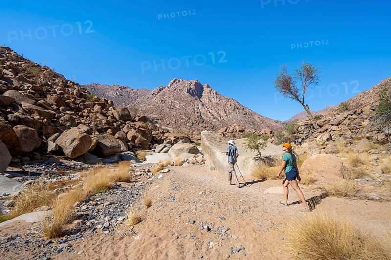 Tourist with guide on the White Lady Trail, Tsisab Gorge, desert landscape, Brandberg, Erongo, Damaraland, Namibia