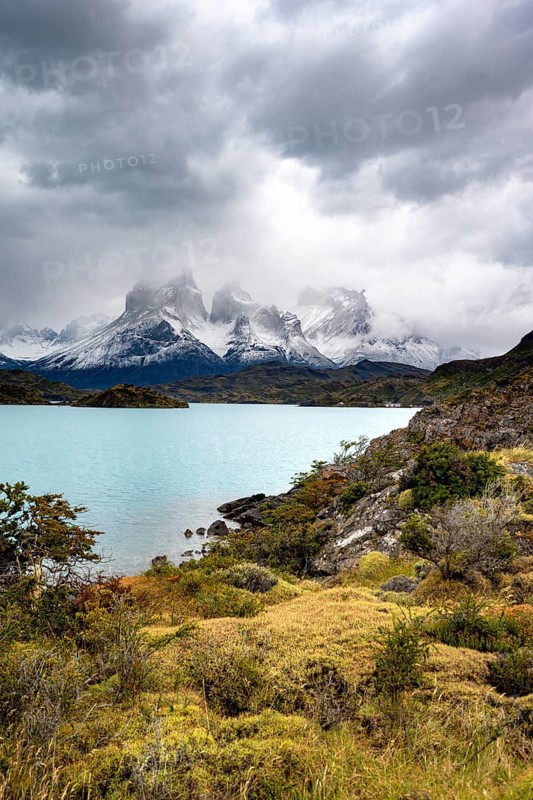 Cloudy mountain range Cuernos del Paine, shore of the blue lake Lago Pehoe in the evening light, dramatic sky, Torres del Paine National Park, Chile