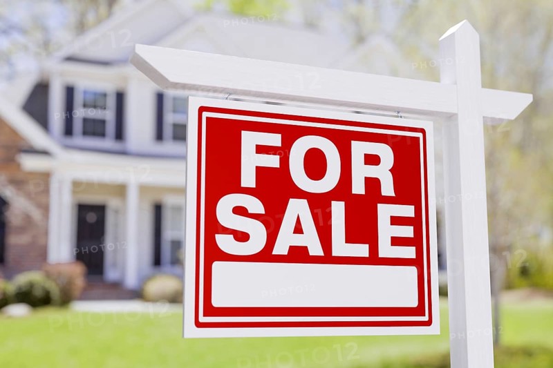 For sale real estate sign in front of beautiful house