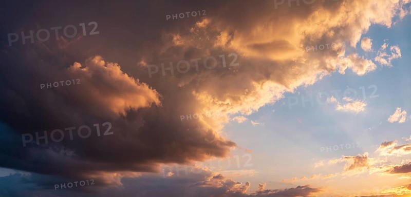 Background image for sky replacement, evening sky with illuminated dark clouds at sunset