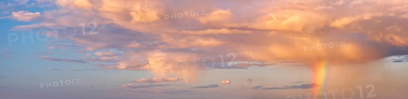 Background image for sky replacement, evening sky with illuminated clouds, rain shower and rainbow at sunset