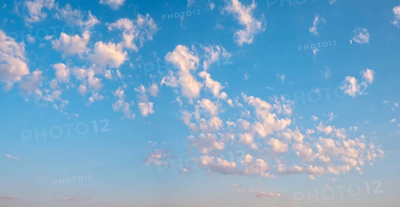 Background image for sky replacement, blue sky with loose white clouds in the evening light