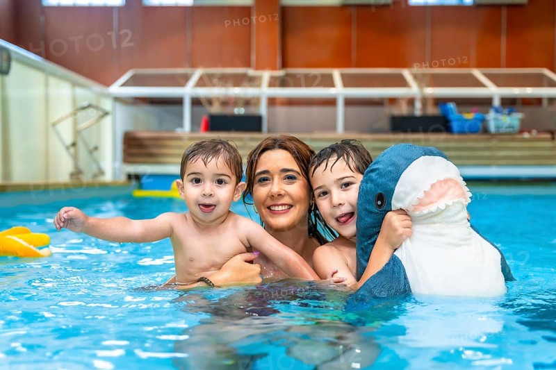 Happy family enjoying time together, playing with inflatable toy in swimming pool during summer vacation