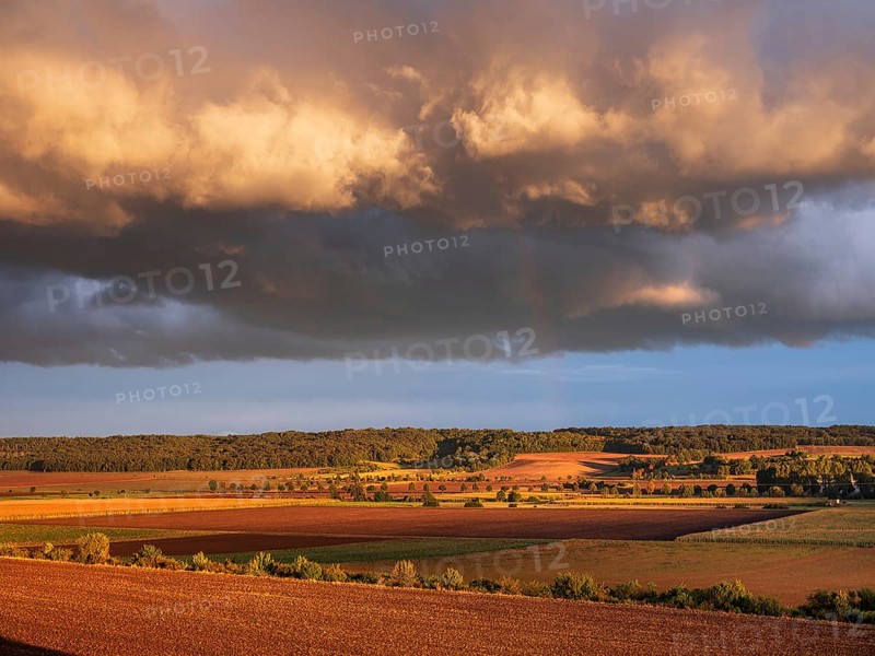 Field landscape in autumn, ploughed fields under dark storm clouds with rainbow in the evening light, Freyburg, Saxony-Anhalt, Germany