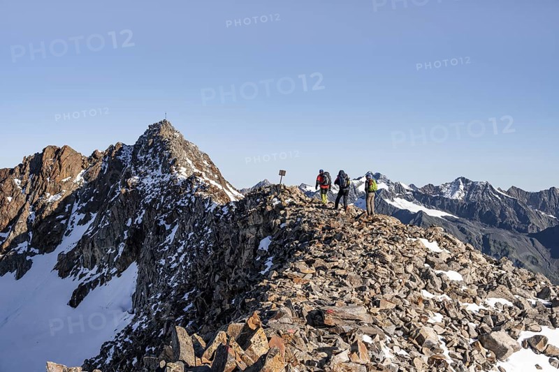 Mountaineer on a ridge, in the background summit Wilder Freiger with summit cross, Stubai Alps, South Tyrol, Italy