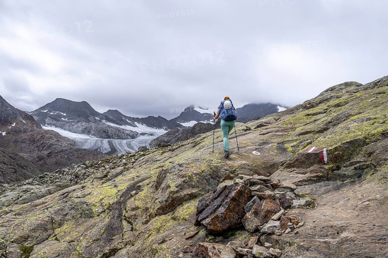 Mountaineer on hiking trail in high mountain landscape, view of glacier tongue of the Übeltalferner, Stubai Alps, South Tyrol, Italy