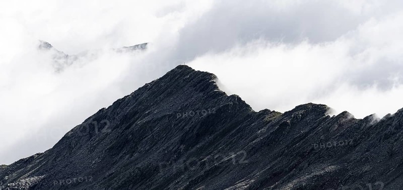 Mountain ridge with summit Zunderspitz and summit cross, cloudy, Stubai Alps, near Ridnaun, South Tyrol, Italy