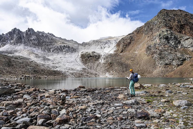 Mountaineer in front of mountain landscape with limestone rocks between granite mountains, mountain lake Hinterer Senner Egetsee and mountain peak of the Moarer Weißen, Seven Lakes Hike, Stubai Alps, near Ridnaun, South Tyrol, Italy