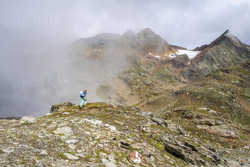 Mountaineer on a hiking trail, cloudy mountain landscape, Egetenjoch, Seven Lakes Hike, Stubai Alps, near Ridnaun, South Tyrol, Italy