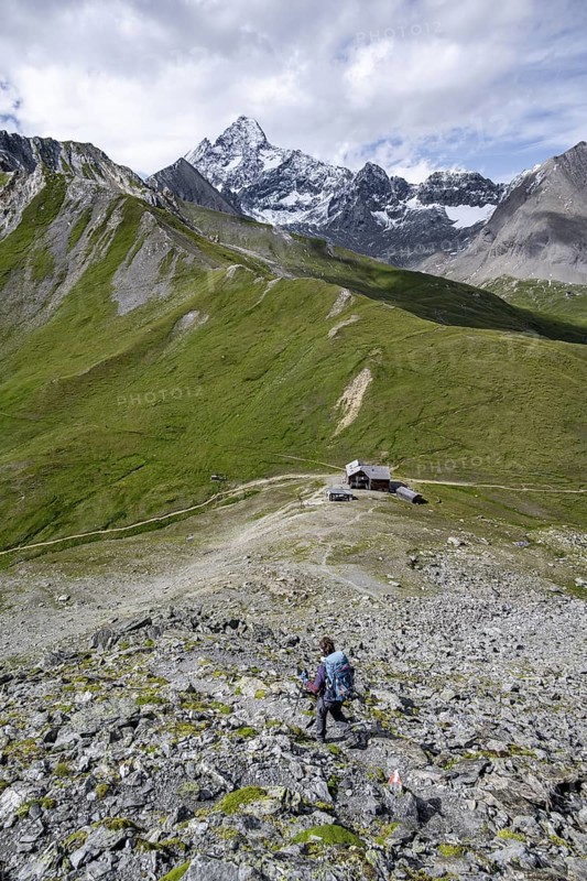 Mountaineer on hiking trail, Glorerhütte mountain hut and mountain peak in the background, Wiener Höhenweg, Schober Group, Hohe Tauern National Park, Carinthia, Austria