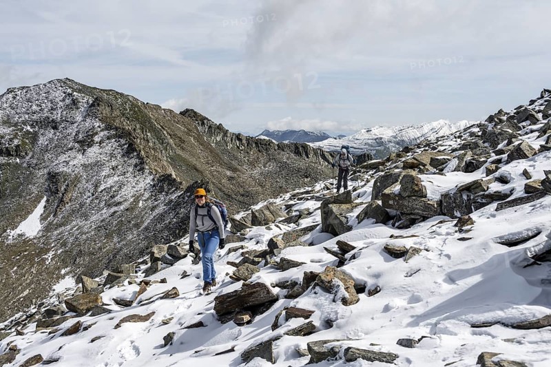 Two female mountaineers in boulder terrain with fresh snow in summer, ascent to the summit Böses Weibl, Wiener Höhenweg, Schober group, Hohe Tauern National Park, Carinthia, Austria