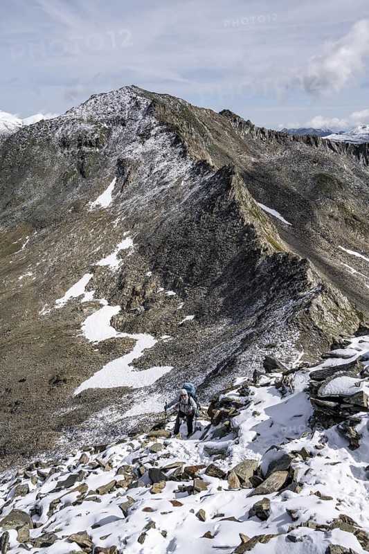 Mountaineer in blocky terrain with fresh snow in summer, ascent to the summit Böses Weibl, Wiener Höhenweg, Schober group, Hohe Tauern National Park, Carinthia, Austria