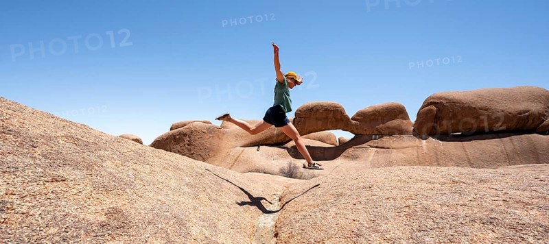 Tourist jumping over rocks, rock formation, Pontok Mountains, Spitzkoppe, Great Spitzkuppe Nature Reserve, Namibia