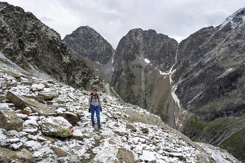 Mountaineer on steep rocky mountain landscape with fresh snow in summer, behind mountain peaks Großer Friedrichskopf and Georgskopf, ascent to Hornscharte, Schober group, Hohe Tauern National Park, Carinthia, Austria
