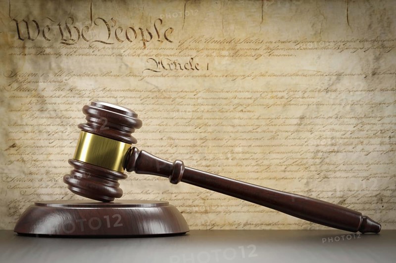 United states constitution on wall with gavel resting on table in front