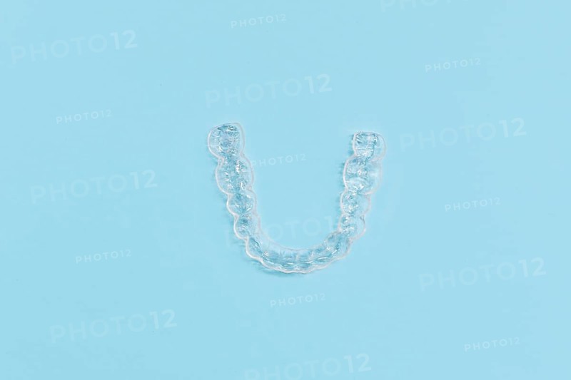 Top view of customized transparent dental teeth bite guard clear aligners for lower jaw on blue background