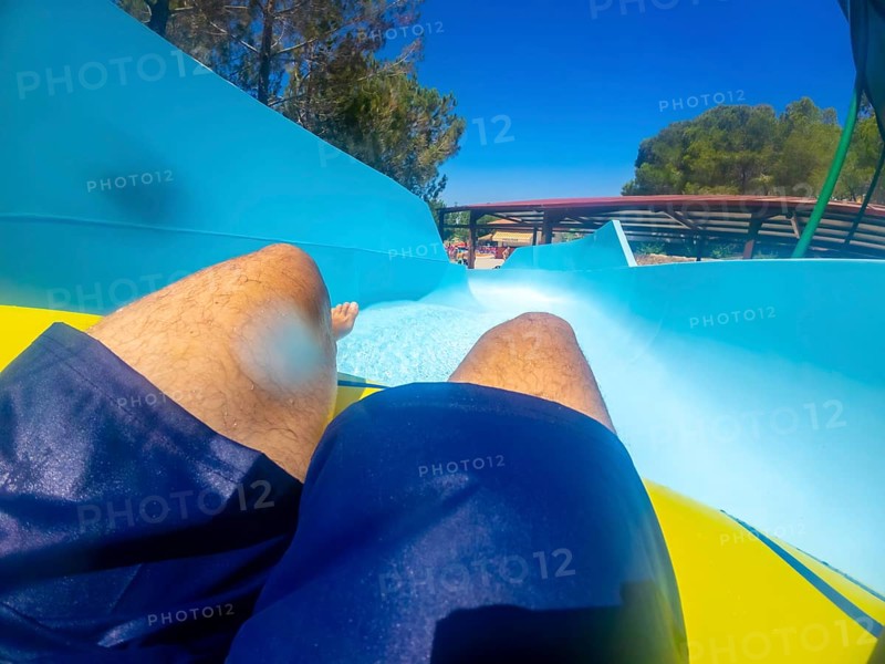Point of view of a man sliding down a thrilling waterslide at an aquatic park, enjoying summer holidays filled with fun and excitement