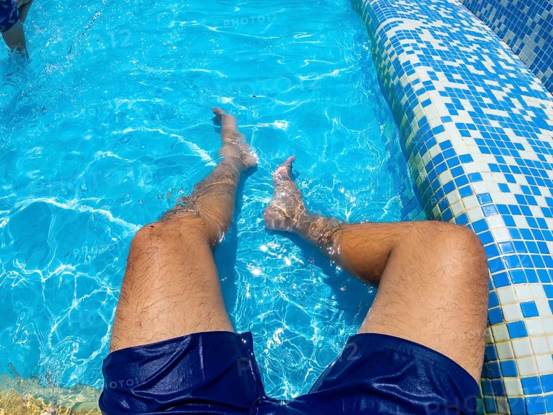 Man relaxing in a blue swimming pool, enjoying the refreshing water on a sunny summer day, embracing a carefree vacation vibe