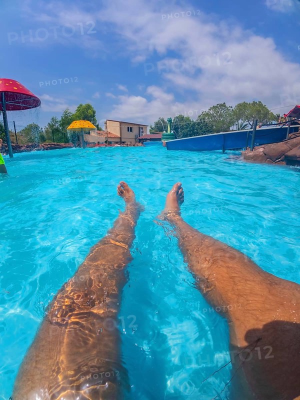 Pov shot of a man relaxing in a swimming pool at a water park, enjoying the summer sun and the refreshing water