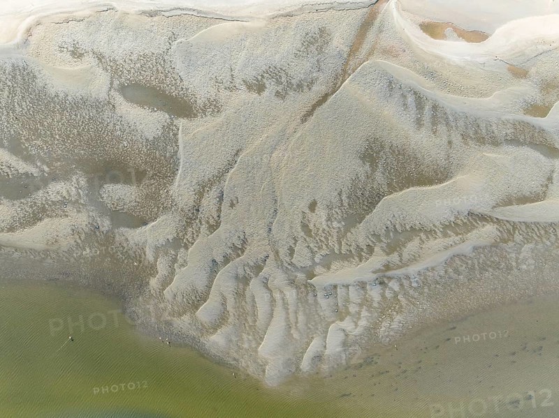 Low tide patterns and Greater Flamingos (Phoenicopterus ruber) at the Walvis Bay Lagoon. Aerial view. Drone shot. Namibia