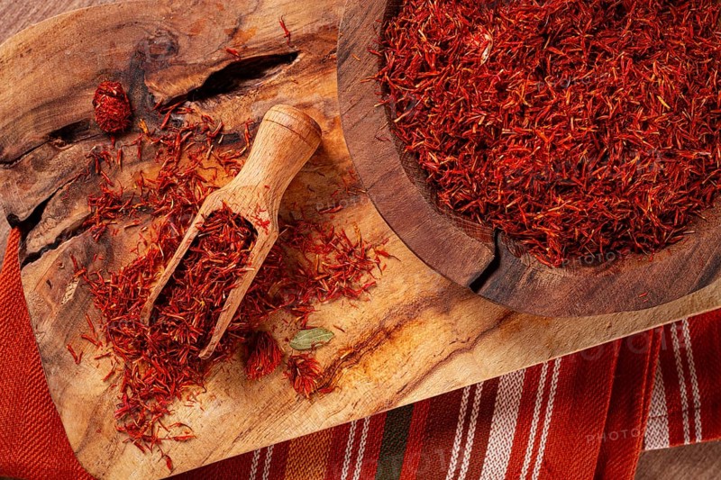 Spice saffron threads, in a wooden bowl, on a wooden table, top view, close-up