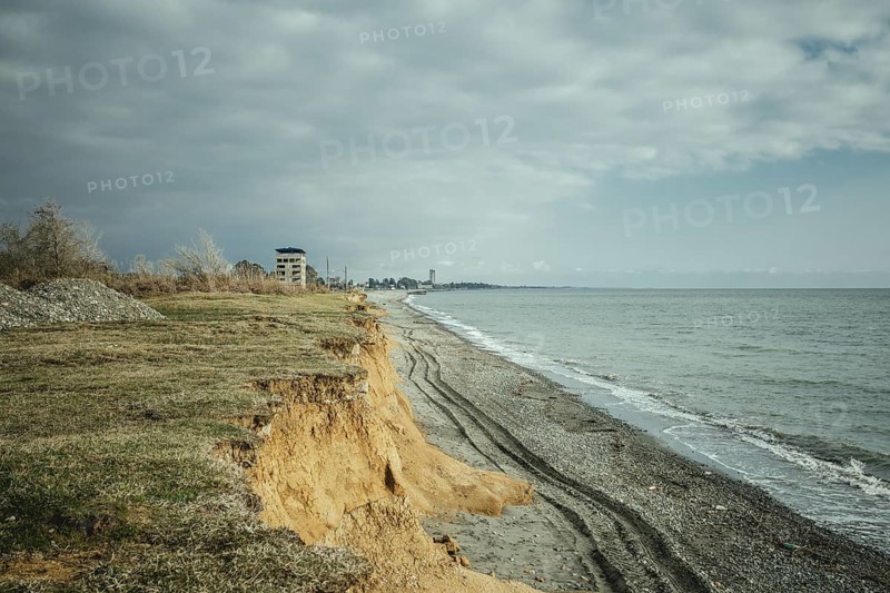 Beach and view of the city. The higher building is the 16-florr-building, as locals call it. Investors wanted to build a hotel there, but when the war broke out, the project was abandoned, Ochamchira, Abkhazia, Georgia