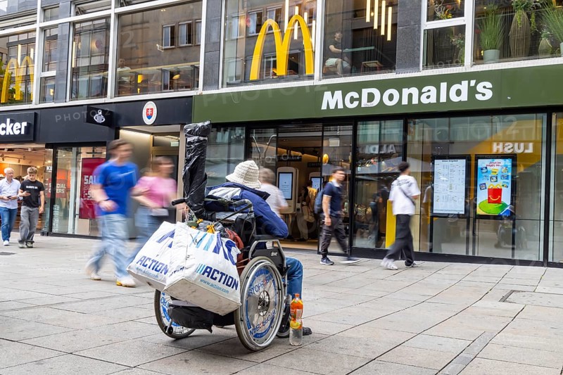 A man in a wheelchair in the Königstraße pedestrian zone in front of a branch of the McDonald's fast food chain. Stuttgart, Baden-Württemberg, Germany