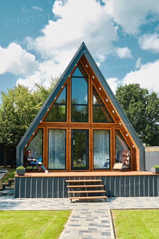 Young woman sitting on a folding chair on the terrace of a tiny house