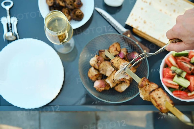 Overhead view of removing kebab from skewer with a fork