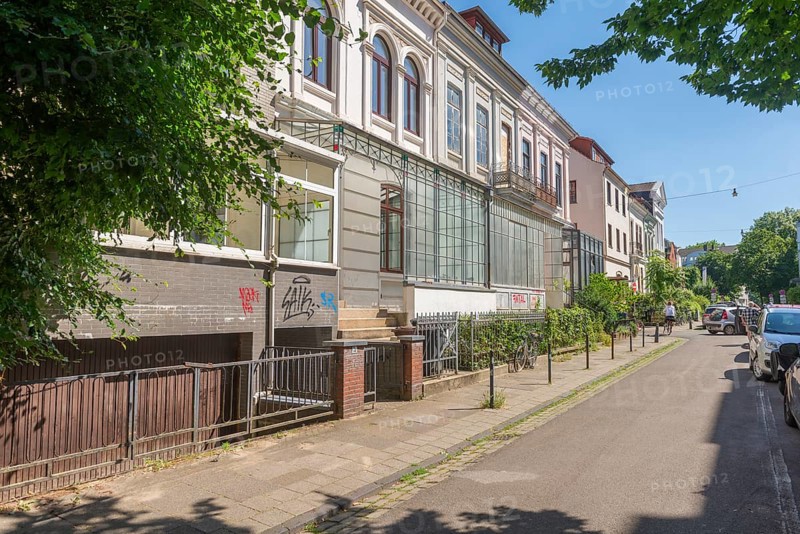Residential street in a popular residential neighbourhood, eastern suburb, Wilhelminian style building, traffic-calmed, facades, glass porch, trees, sunshine, parked cars, Bremen, Germany
