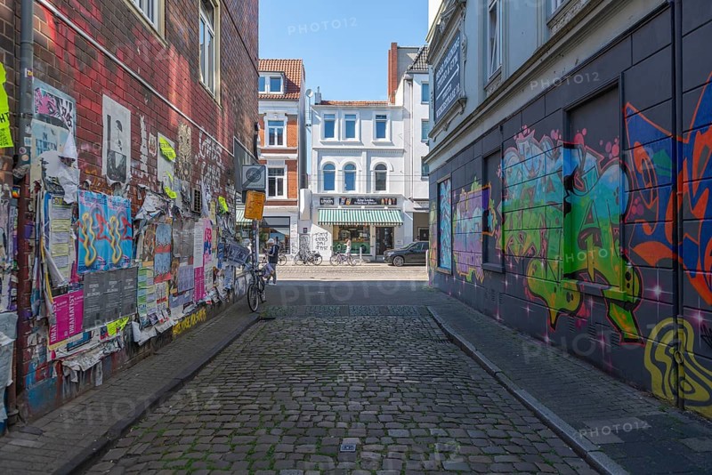 Residential street in the Ostertor neighbourhood a popular residential area, eastern suburb, Wilhelminian style buildings, graffiti, narrow street, cobblestones, advertising posters, traffic-calmed, facades, Bremen, Germany