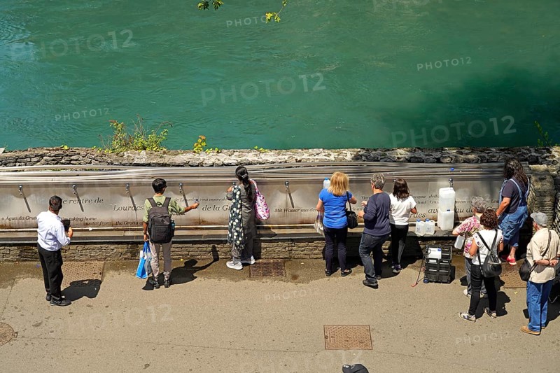 Pilgrims at the fountain with the holy water from the spring of the Marian pilgrimage site of Lourdes, Pyrenees, France