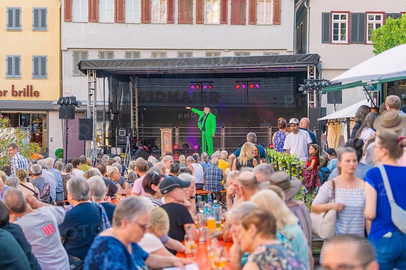 A man in a green suit speaks from a stage to a large crowd, 950 years Weil der Stadt ceremony, Böblingen district, Germany