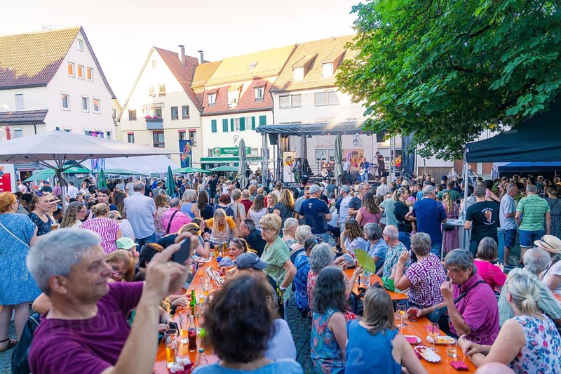 Large crowd enjoying an outdoor concert with seats and surrounding houses, 950 years Weil der Stadt ceremony, Böblingen district, Germany