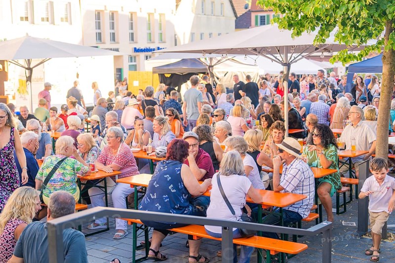 People enjoying a summer get-together at outdoor beer tables under trees, 950 years Weil der Stadt ceremony, Böblingen district, Germany