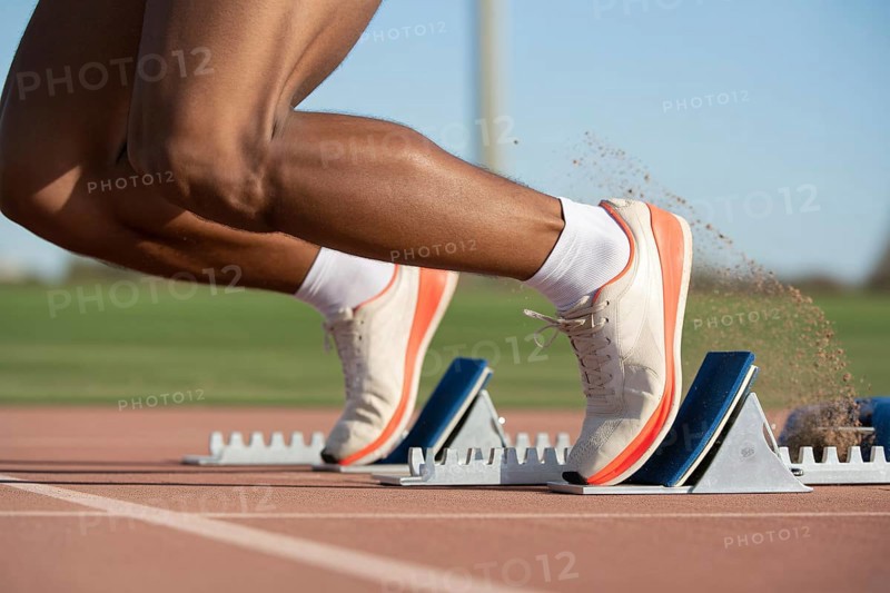 Close-up of athlete in running shoes on starting block at running track. Concept of speed and competition. Generative ai, AI generated