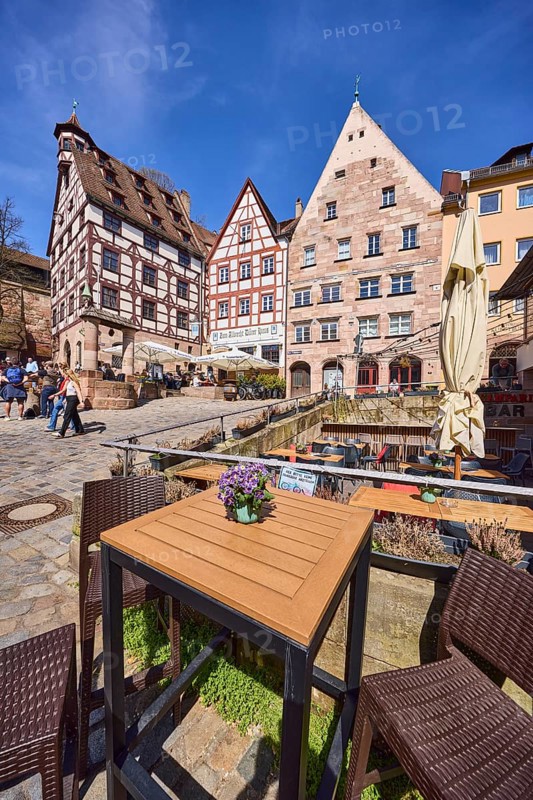 Pilatushaus, town house, late Gothic architectural style, historic buildings, half-timbered houses, cobblestones, outdoor area of a restaurant with tables, chairs and parasol, square, pedestrians as secondary motif, super wide angle, blue sky, Beim TiergÃ¤rtnertor, Obere Schmiedgasse, TiergÃ¤rtnertorplatz, cirrostratus clouds, Nuremberg, Middle Franconia, independent city, Bavaria, Germany