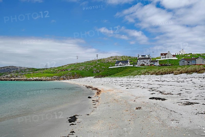 Quiet sandy beach with neighbouring houses under a slightly cloudy sky, Outer Hebrides, Eriksay, Scotland, United Kingdom