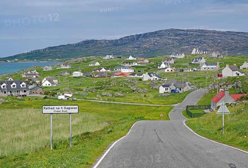 Small village in a hilly landscape with white houses and a main road, Outer Hebrides, Eriksay, Scotland, United Kingdom