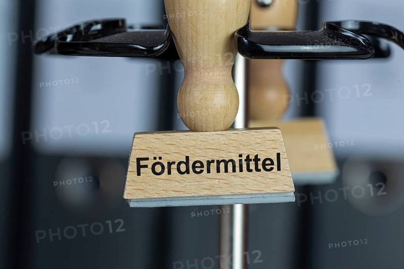 Stamp with added text FÃ–RDERMITTEL on a desk (symbolic image)