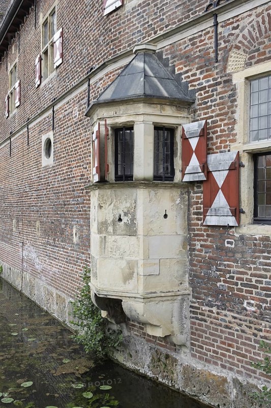 Medieval bay window on a brick wall with red shutters and moat, Raesfeld Castle, MÃ¼nsterland, North Rhine-Westphalia, Germany