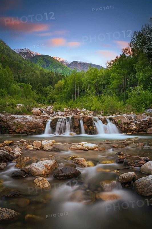 View of a waterfall of the Rio Plima stream in the evening light, long exposure, landscape photo, nature photo, portrait format, forest, trees, Dolomites, South Tyrol, mountains, Laces, Morter, Italy