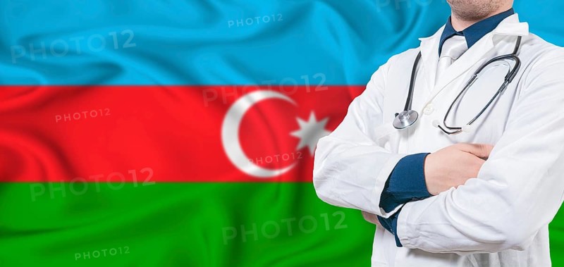 Azerbaijan healthcare concept. Male doctor on Azerbaijan flag. Doctor with crossed arms on Azerbaijan flag