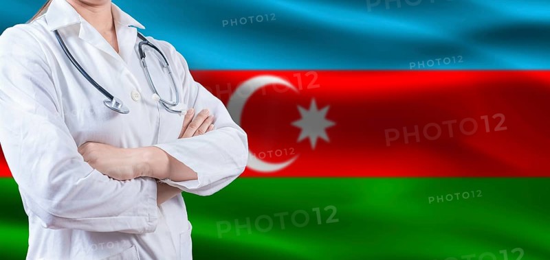 Doctor with crossed arms on Azerbaijan flag. Azerbaijan health and care concept. Female doctor on Azerbaijan flag