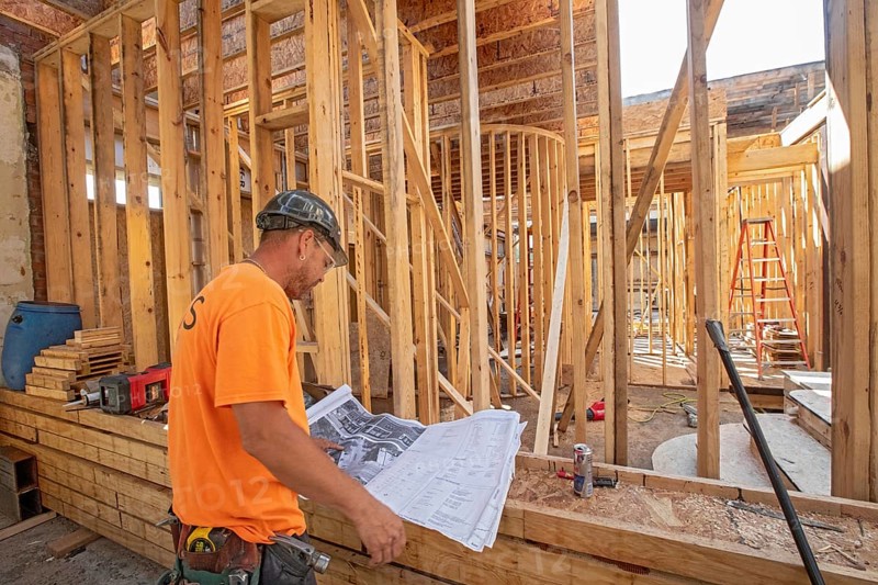 Detroit, Michigan - Jay Newcomb III looks over architectural plans as workers rehab a long-vacant and crumbling commercial building in the Morningside neighborhood. The project, called Ultreia, will contain first floor commercial space and apartments above