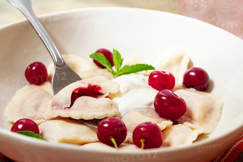 Traditional dumplings with cherries and yogurt, close-up, no people